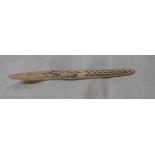 A carved bone letter opener with Inuit style scrimshaw decoration depicting a caribou pulling a