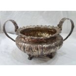 A large antique silver sugar bowl with cast rim, embossed decoration and flanking loop handles -