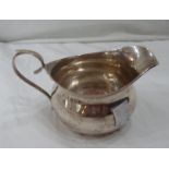 A silver cream jug with slender scroll handle - small dent