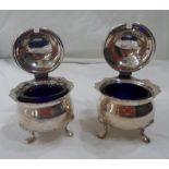 A pair of silver mustard pots with hinged flip-tops and blue glass liners - dents -Sheffield, 1902