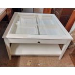A 93cm modern white painted two tier display table with glass top, set on moulded tapered supports