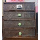 A vintage four drawer filing chest with textured faux wood covering and green early plastic handles