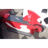 A vintage wooden child's fairground ride seat in the form of a racing motorbike with red and white