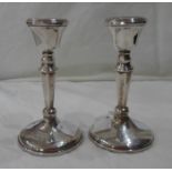 A pair of 10cm high silver candlesticks with loaded circular bases - one a/f