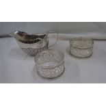 A small silver cream jug of semi-reeded oval design - sold with a pair of silver napkin rings with