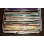 A box containing assorted LP records including Simon & Garfunkel, The Prodigy, Tom Jones, etc.