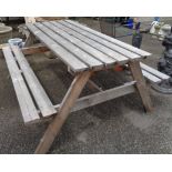 A wooden garden table with integral flanking benches