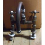 An old brass hot and cold mixer tap with porcelain bosses