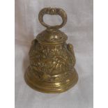 A cast brass table hand bell decorated with stork and lilypad motifs and a grotesque fish handle -