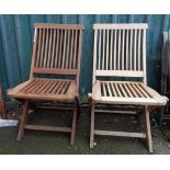 A pair of teak folding garden chairs with slatted backs and seats