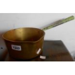 An old brass sauce pan with green painted iron handle