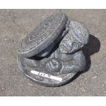 A small concrete garden figure in the form of a man emerging from a manhole cover