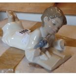 A Nao porcelain figurine depicting a young boy reading a book to his puppy