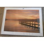 A pair of silvered framed decorative coloured prints, depicting a jetty on a lake and the other sand