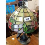 A cast metal table lamp with bronzed finish and Tiffany style stained glass shade