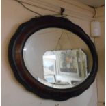 A 1920's wood grained framed bevelled oval wall mirror with serpentine border