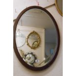 An Edwardian mahogany and strung bevelled oval wall mirror