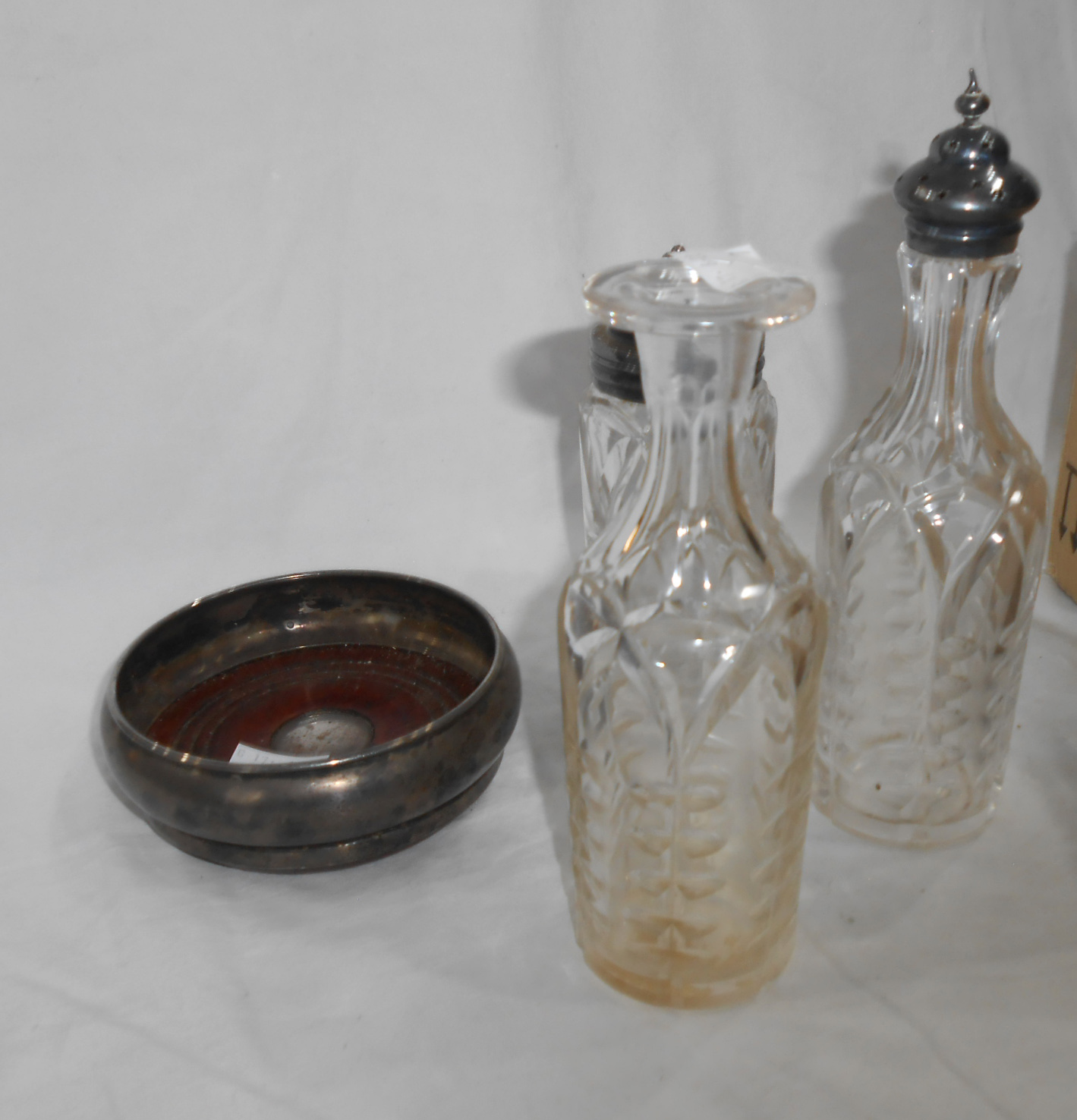 A silver wine coaster with turned wood base - sold with three cut glass cruet bottles