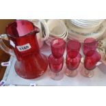 A cranberry jug of cylindrical form - sold with six small glasses with cranberry bowls and clear