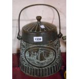 An Arts and Crafts Movement beaten copper coal bucket with lid with repousse central panel depicting