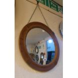 A 20th Century stained oak framed convex wall mirror with applied moulded decoration