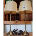 A pair of modern metal table lamps of slender candlestick form with brassed finish