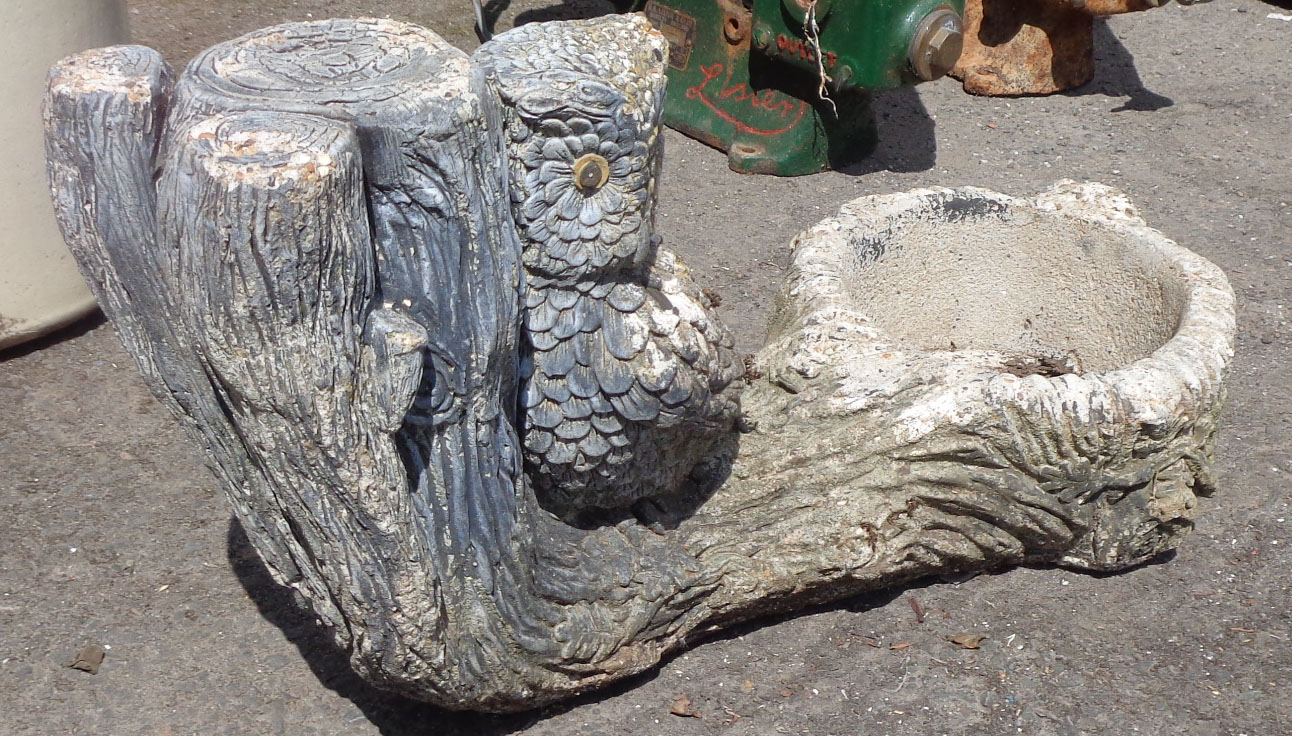 A small concrete figural planter depicting an owl perched upon a fallen tree trunk