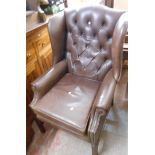 A late 20th Century antique style wingback armchair upholstered in studded brown leather, set on