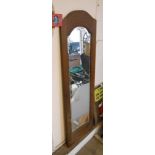 A 1.33m stained wood framed narrow bevelled oblong wall mirror with arched top plate