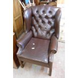 A late 20th Century antique style wingback armchair upholstered in studded brown leather, set on