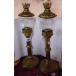 A pair of early 20th Century brass spring loaded candlesticks with glass shades and pierced cap lids