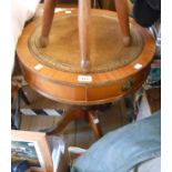A 50cm diameter reproduction mahogany drum table with leather inset top and three drawers, set on