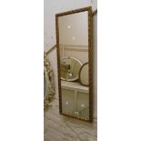 A modern gilt framed narrow oblong wall mirror with decorative border