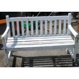 A white painted wood two seater garden bench with slatted back and seat