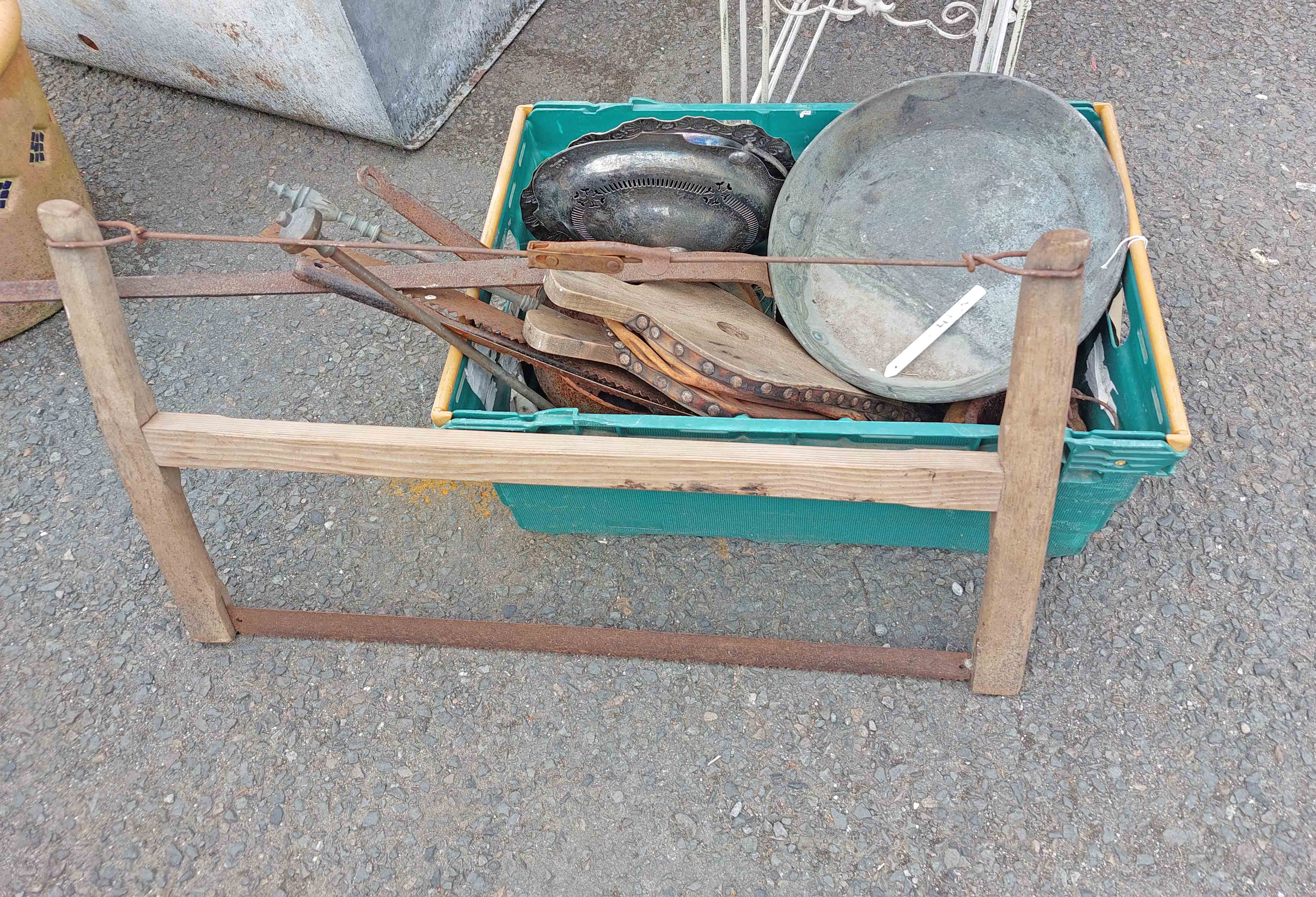 A crate containing assorted items including bellows, saw, etc.