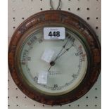 A late Victorian carved oak cased circular wall barometer with printed ceramic dial marked for