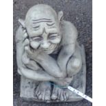 A cast concrete garden statue of a gargoyle in thoughtful pose