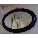 A 1920's wood grained framed bevelled oval wall mirror with serpentine border