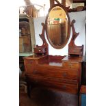 A 1.04m early 20th Century stained mahogany dressing chest with bevelled oval swing mirror, flanking