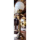 A brass oil lamp of Corinthian column form with double burner, clear glass chimney and white