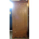 A 92cm modern pine wardrobe with hanging space enclosed by a panelled door with long drawer under,