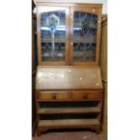 A 1.07m early 20th Century oak bureau/bookcase with decorative leaded glazed panel doors to top over