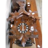 A vintage polished wood cased cuckoo wall clock with twin cast metal pinecone pattern weights -