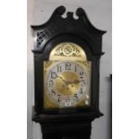 A 20th Century ebonised longcase clock with blind fretwork decoration and brassed arched dial with