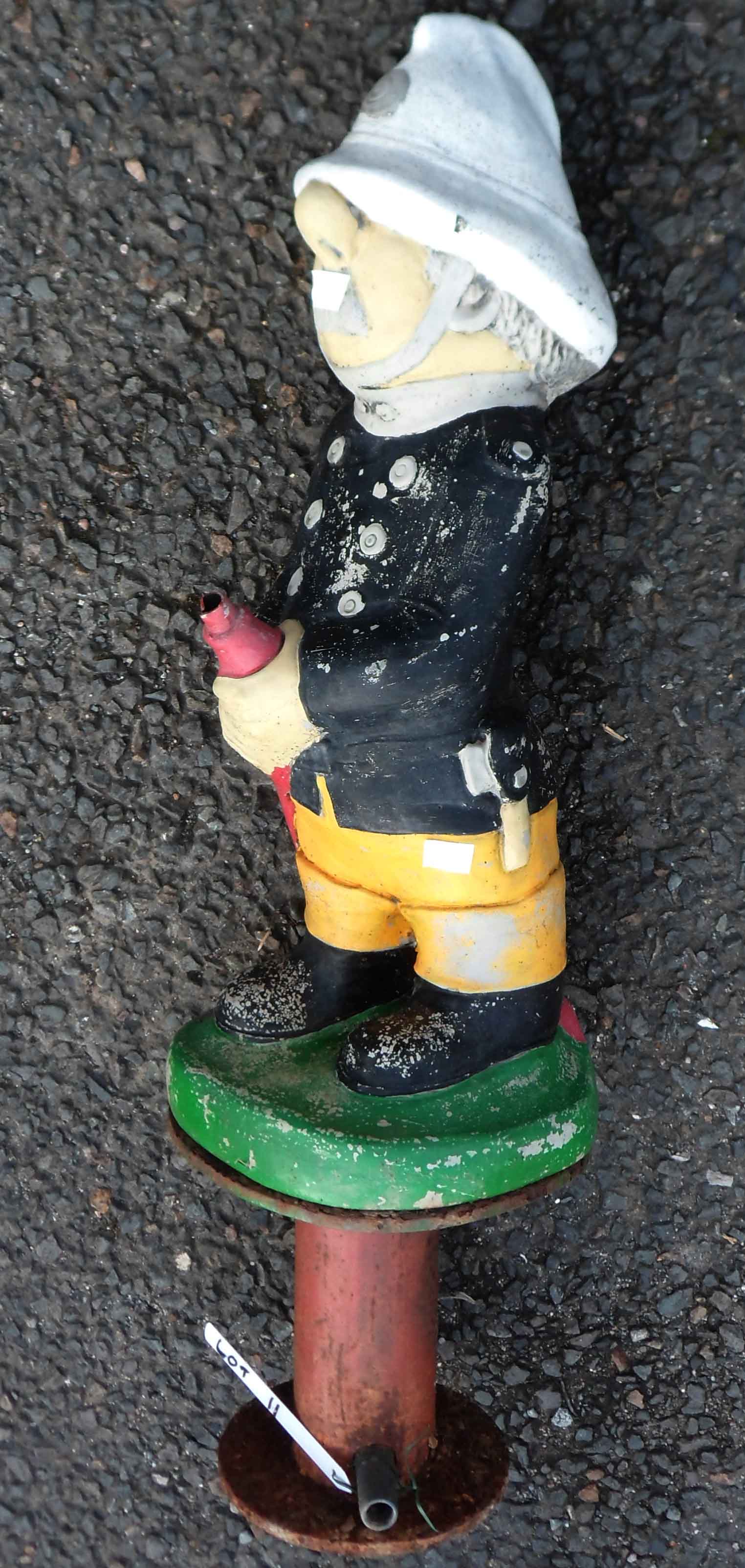 A vintage concrete garden fountain in the form of a fireman with painted finish, set on metal base