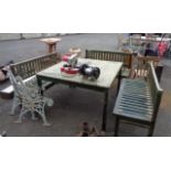 A large teak garden table and three benches with part green woodstained finish