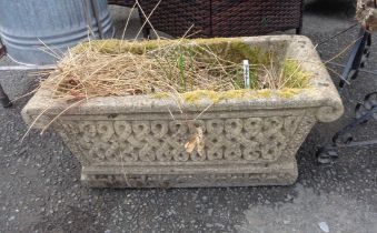 A concrete garden planter of trough form with repeat knot decoration and cushion ends