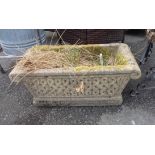 A concrete garden planter of trough form with repeat knot decoration and cushion ends