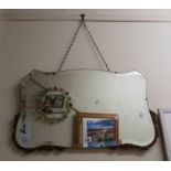 A vintage frameless wall mirror with shaped bevelled plate and applied carved wood floral scoll