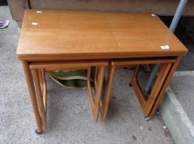 A teak mid Century nest of three tables, the largest with fold-over top, set on Shepherd casters